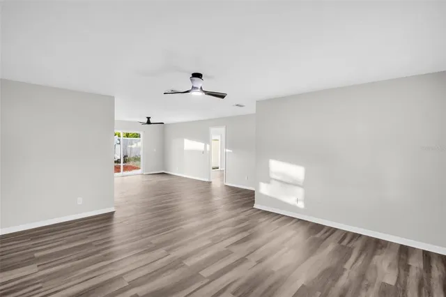 a view of an empty room with a window and wooden floor