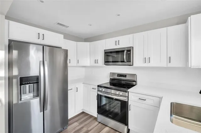 a kitchen with white cabinets stainless steel appliances and sink