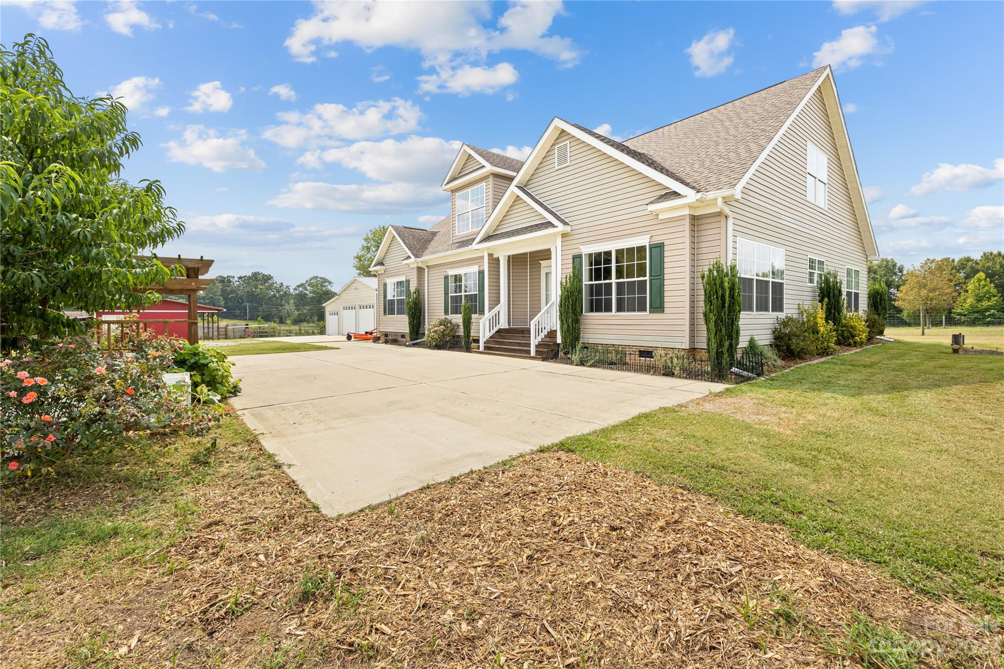 1131 Sikes Mill Road Monroe, NC 28110 - Photo 4 of 43 a view of a white house next to a yard with big trees