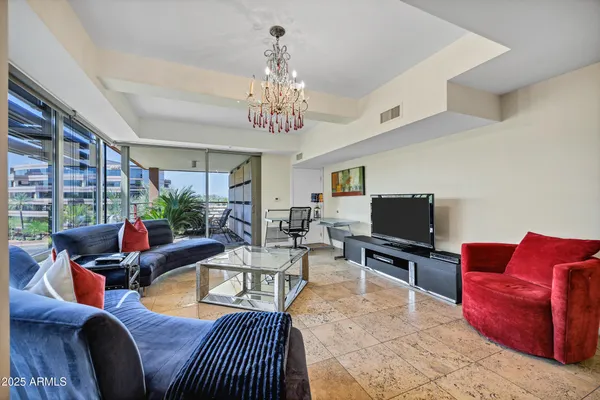 a living room with furniture a chandelier and a flat screen tv