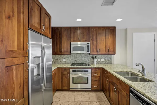 a kitchen with granite countertop stainless steel appliances a stove sink and refrigerator