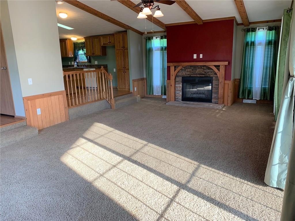 52 Willow Road Claysville, PA 15323 - Photo 3 of 25 A view of the huge living room with wood burning fireplace and vaulted ceilings with the woodlike beams and ceiling fan. You can see the kitchen off to the left and the access to the wrap around deck off to the right.