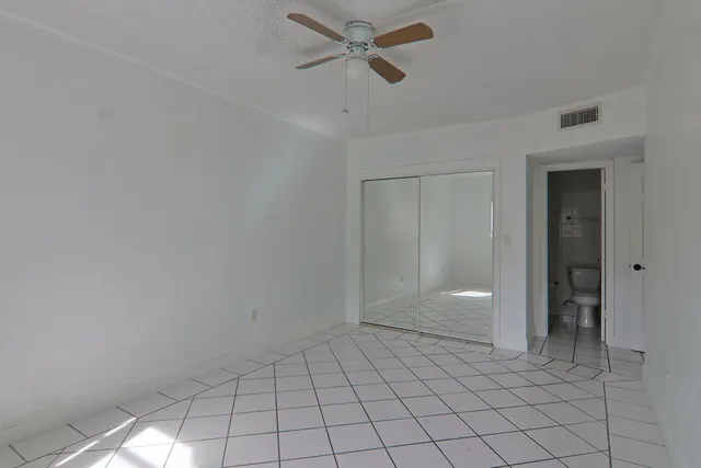 an empty room with closet and a chandelier fan