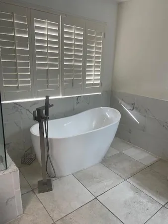 a white bath tub sitting in a bathroom next to a window