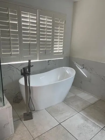 a white bath tub sitting in a bathroom next to a window
