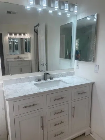 a bathroom with a granite countertop sink a large mirror and a