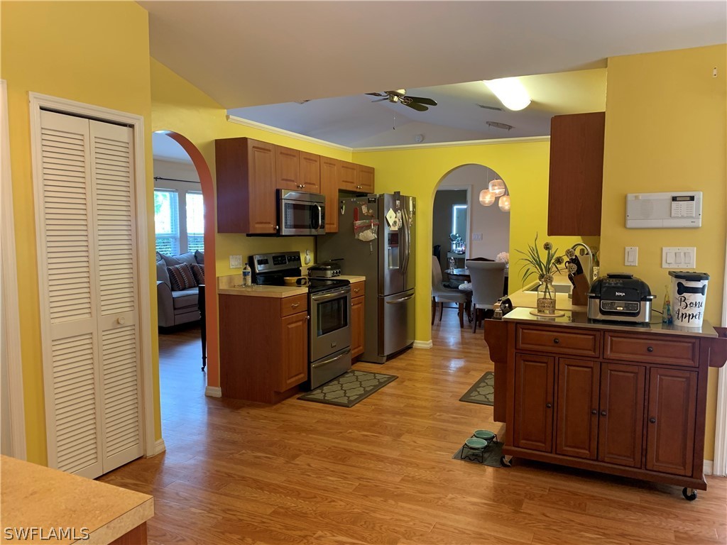 17560 Lee Road Fort Myers, FL 33967 - Photo 13 of 34 a living room with stainless steel appliances kitchen island granite countertop a refrigerator a sink dishwasher and wooden cabinets with wooden floor