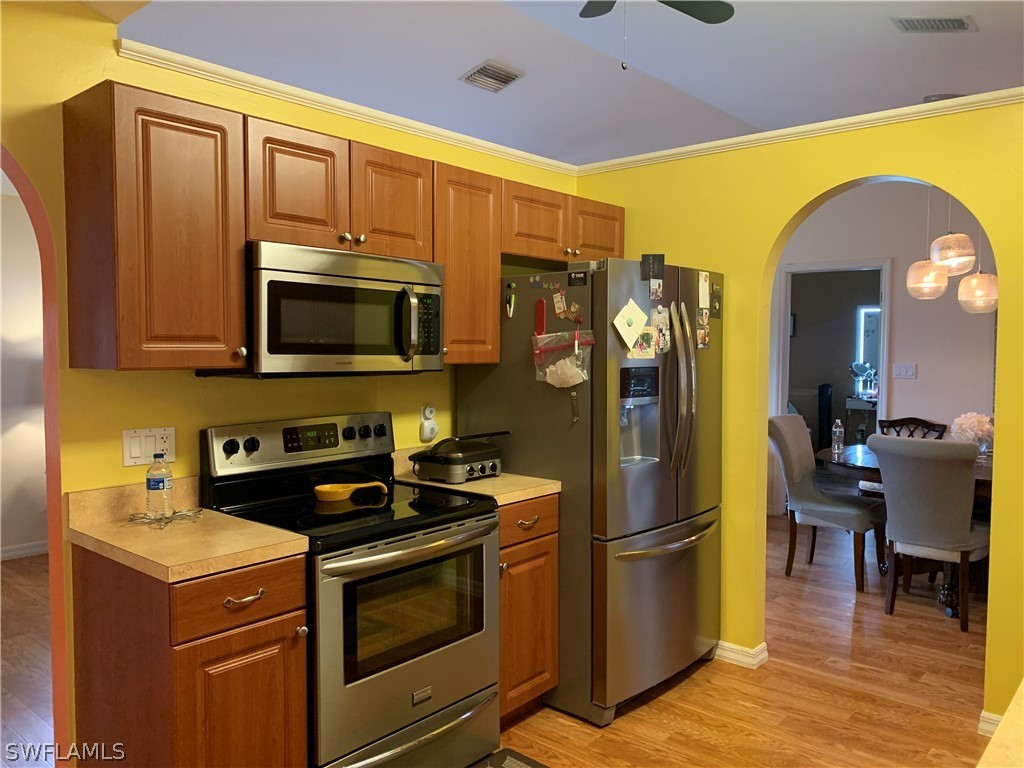 17560 Lee Road Fort Myers, FL 33967 - Photo 10 of 34 a kitchen with stainless steel appliances granite countertop a stove top oven a sink dishwasher a refrigerator and cabinets with wooden floor