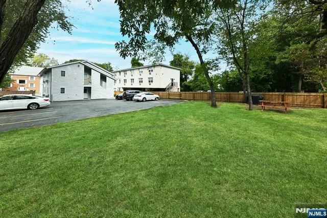 a view of a white house in front of a big yard with large trees