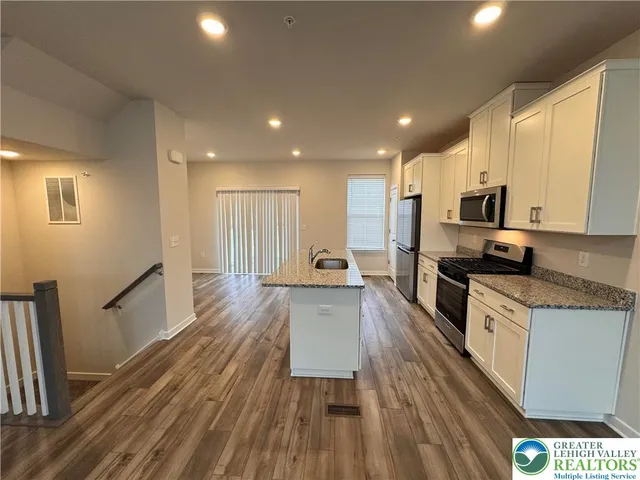 a large kitchen with a center island wooden floor stainless steel appliances and cabinets