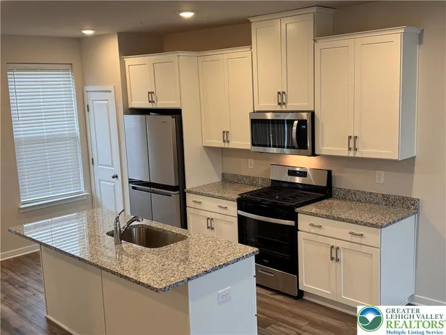 a kitchen with granite countertop a sink stove and refrigerator
