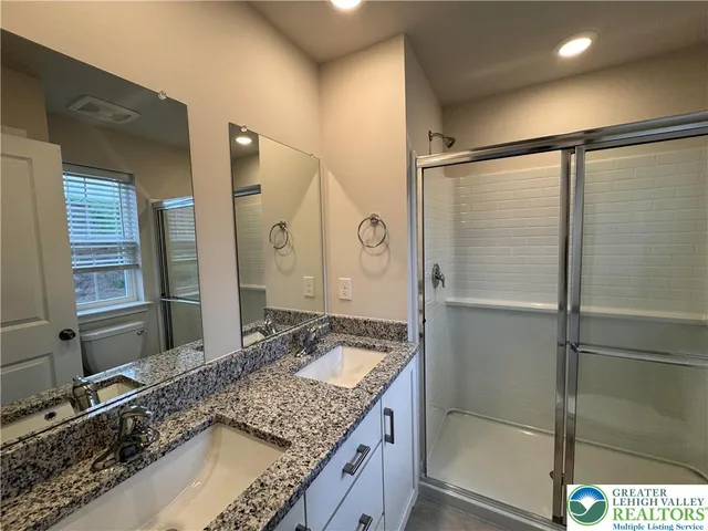 a bathroom with a granite countertop sink mirror and shower