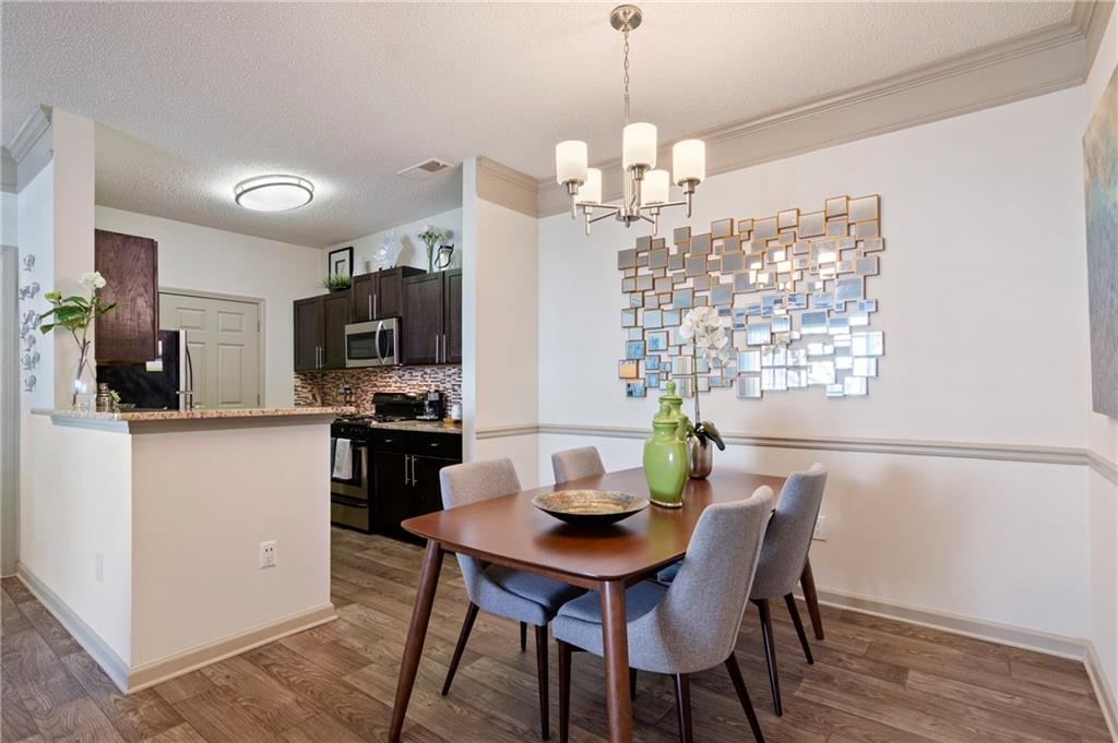 10055 Jones Bridge Road, Unit 206 Johns Creek, GA 30022 - Photo 3 of 28 a view of a dining room with furniture a chandelier and wooden floor