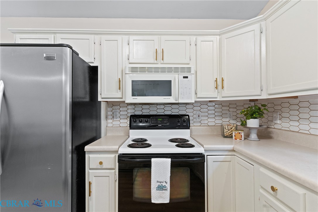 1973 Buckner Road Bumpass, VA 23024 - Photo 18 of 36 Kitchen featuring range with electric stovetop, freestanding refrigerator, light countertops, white microwave, and tasteful backsplash