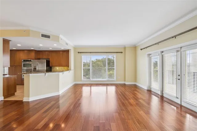 a view of an empty room with wooden floor and a window