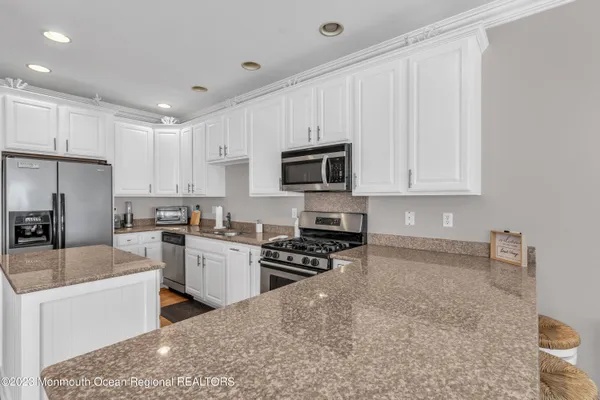 a kitchen with granite countertop a stove sink microwave and refrigerator
