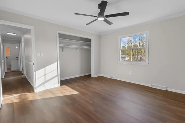 a view of an empty room with wooden floor and a window