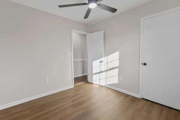 an empty room with wooden floor cabinet and windows