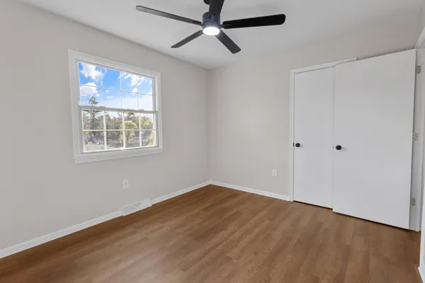 a view of empty room with wooden floor and fan