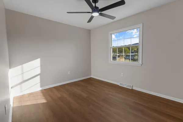 an empty room with windows and fan