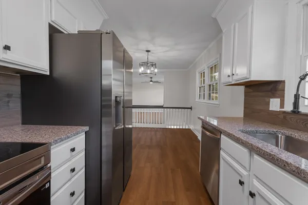 a kitchen with stainless steel appliances granite countertop a refrigerator a sink dishwasher a stove and white countertops with wooden floor