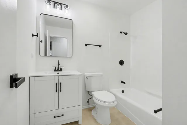 a bathroom with a toilet a sink a mirror and shower