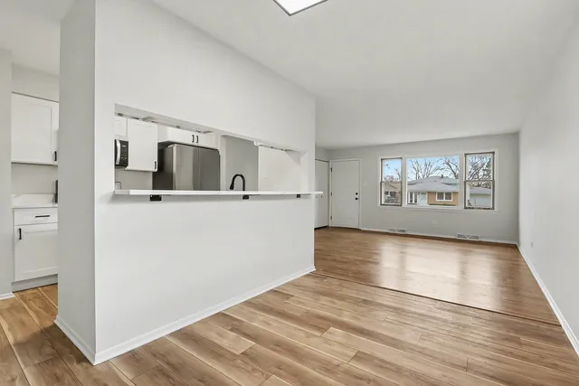 a view of a kitchen with wooden floor and a hallway