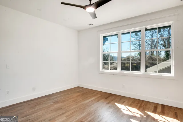 an empty room with wooden floor and windows