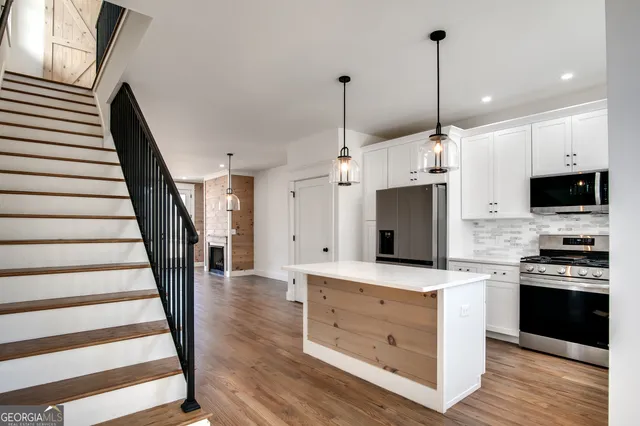 a view of a kitchen with kitchen island stainless steel appliances and wooden floor
