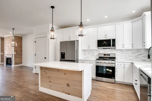 a kitchen with stainless steel appliances kitchen island granite countertop a stove a sink and a refrigerator with wooden floor