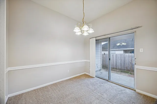 a view of an empty room with chandelier fan