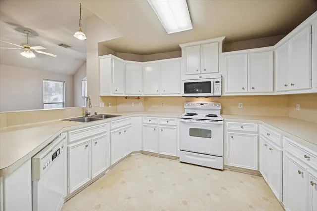 a kitchen with granite countertop white cabinets and white appliances