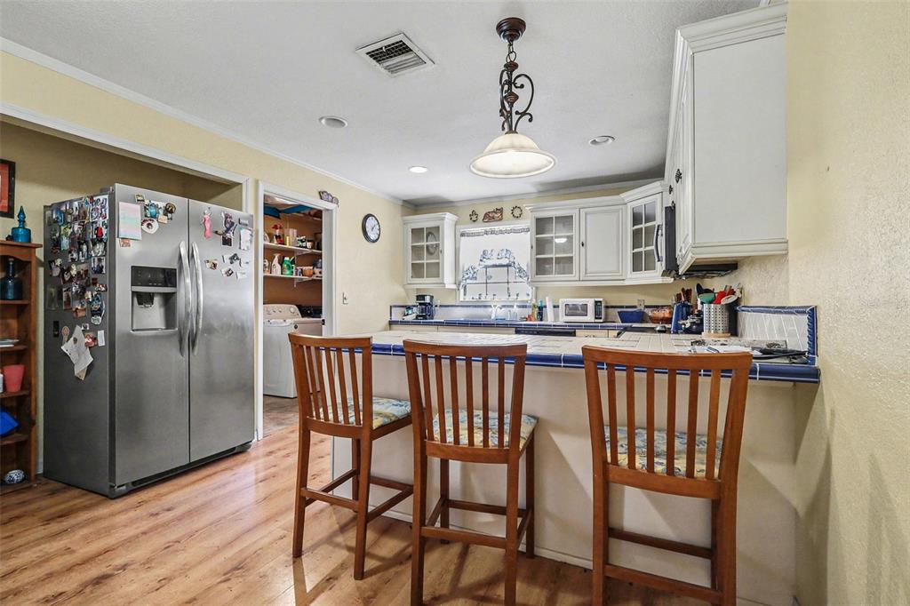 58 Deer Road Frostproof, FL 33843 - Photo 7 of 20 a kitchen with stainless steel appliances granite countertop a refrigerator a sink a stove a dining table and chairs with wooden floor