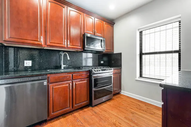 a kitchen with stainless steel appliances granite countertop a stove a sink and a microwave
