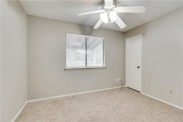 an empty room with a window and a chandelier fan
