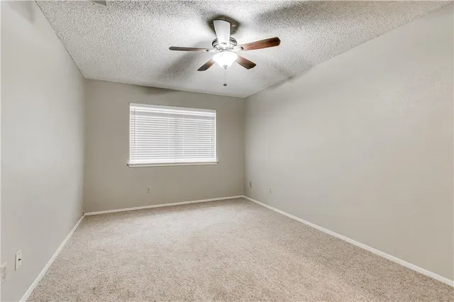 an empty room with a window and a ceiling fan
