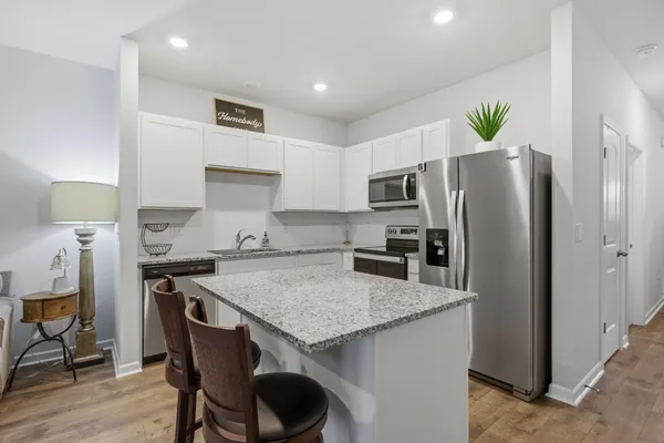 a kitchen with stainless steel appliances white cabinets and wooden floor