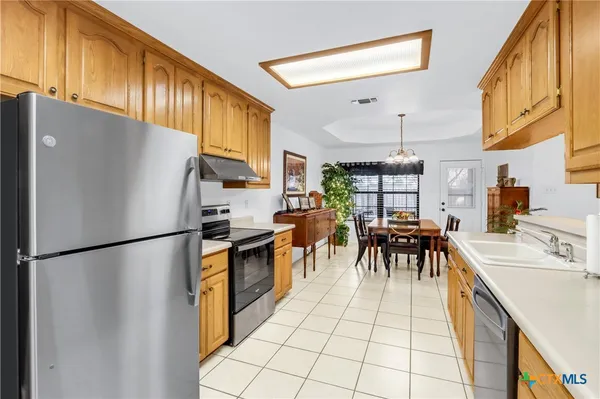 a kitchen with stainless steel appliances granite countertop a refrigerator a sink a stove and a refrigerator