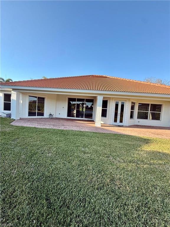 5031 Rustic Oaks Circle Naples, FL 34105 - Photo 2 of 15 Rear view of house featuring a yard and french doors