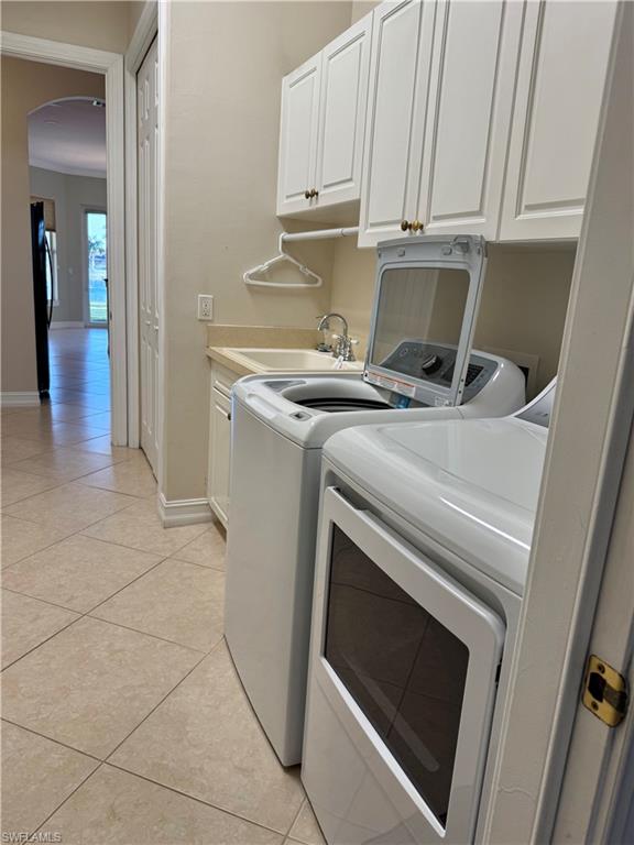 5031 Rustic Oaks Circle Naples, FL 34105 - Photo 5 of 15 Laundry room featuring cabinet space, washer and dryer, arched walkways, light tile patterned floors, and crown molding