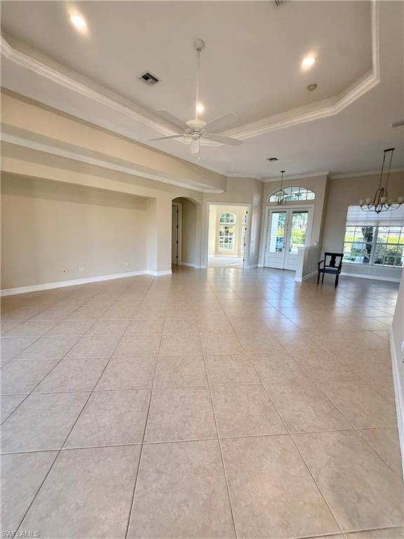 5031 Rustic Oaks Circle Naples, FL 34105 - Photo 6 of 15 Unfurnished living room with french doors, a ceiling fan, light tile patterned floors, ornamental molding, and a raised ceiling