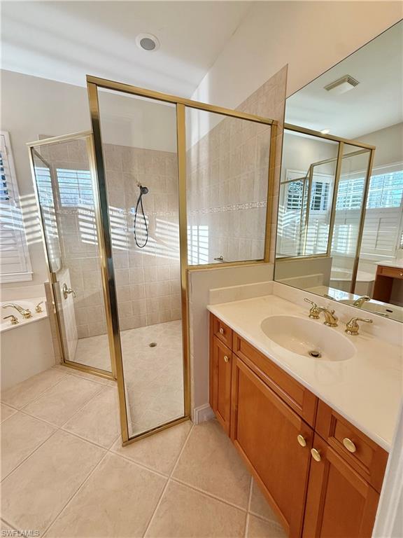 5031 Rustic Oaks Circle Naples, FL 34105 - Photo 9 of 15 Bathroom with vanity, a stall shower, light tile patterned floors, and a bath