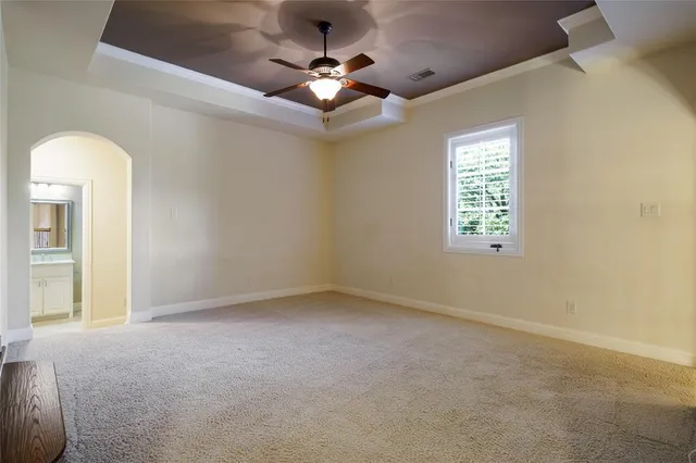 an empty room with a chandelier fan and windows