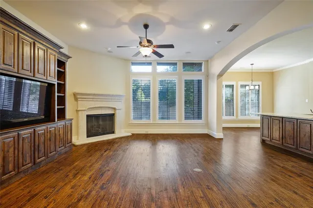 a view of an empty room with wooden floor fireplace and a window