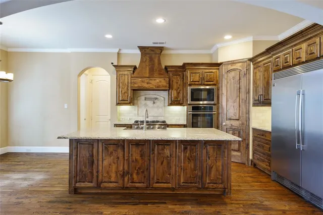 a kitchen with kitchen island a counter top space cabinets and stainless steel appliances