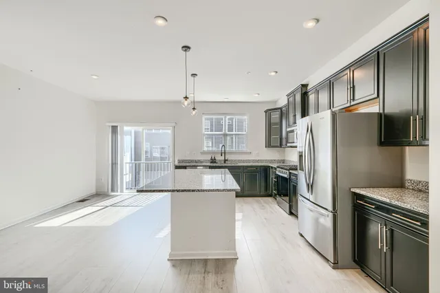 a kitchen with stainless steel appliances kitchen island granite countertop a refrigerator a stove and a sink