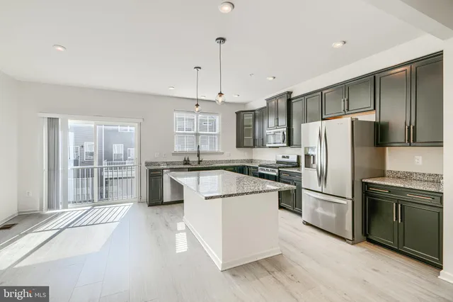 a kitchen with stainless steel appliances granite countertop a refrigerator a stove a sink dishwasher a refrigerator and white cabinets with wooden floor