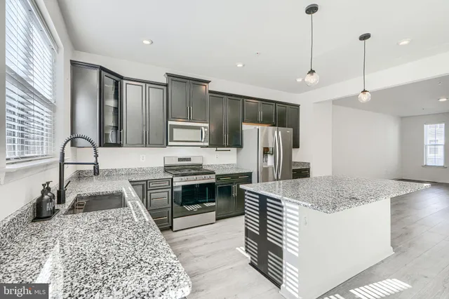 a kitchen with stainless steel appliances granite countertop a sink stove and refrigerator
