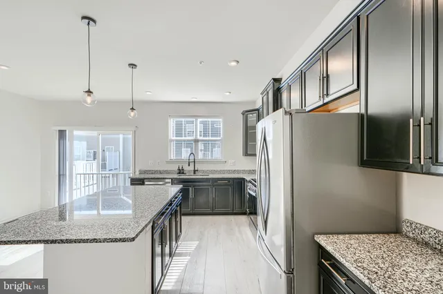 a kitchen with stainless steel appliances granite countertop a refrigerator a sink a stove and dishwasher