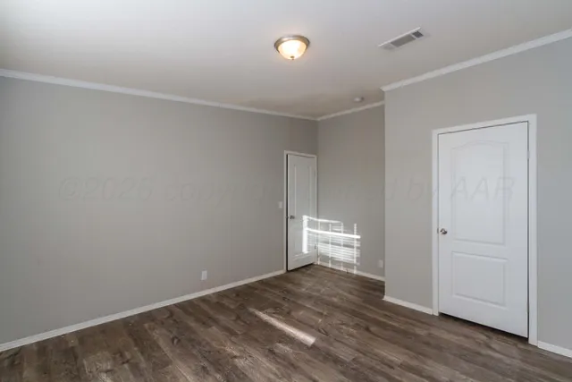 a view of an empty room with wooden floor and windows